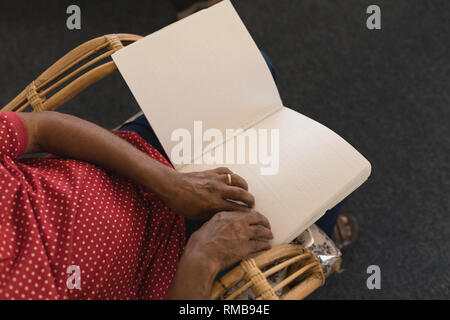 Blind senior man reading a braille book at nursing home Stock Photo