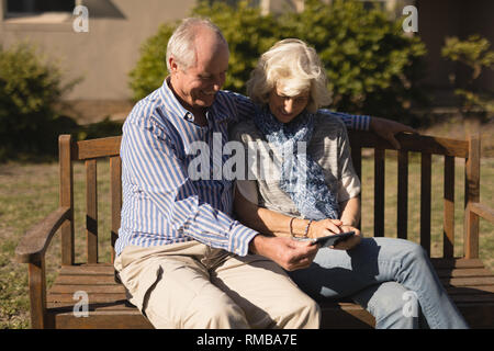 Senior couple using mobile phone in the park Stock Photo