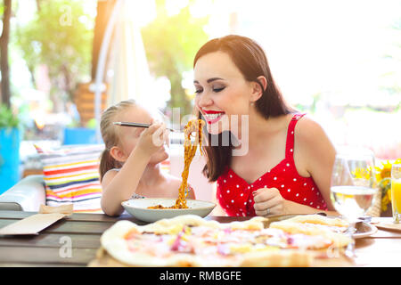 Happy mother and daughter eating spaghetti bolognese in the restaurant together Stock Photo