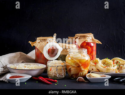 Fermented food. Vegetarian food concept. Cabbage kimchi, tomatoes marinated, sauerkraut sour glass jars over rustic kitchen table. Canned food concept Stock Photo