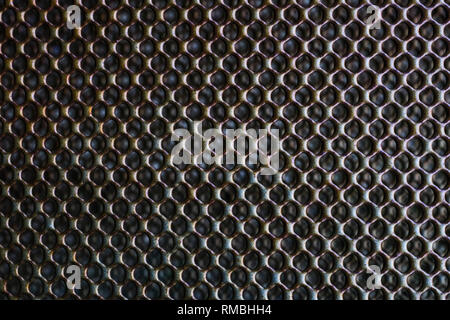 A close up of a black and grey mesh metal with perforated holes Stock Photo