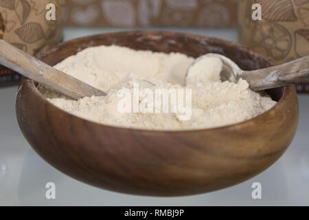 Wholemeal Flour in a Round Wooden Container and Two Wooden Spoons. Stock Photo