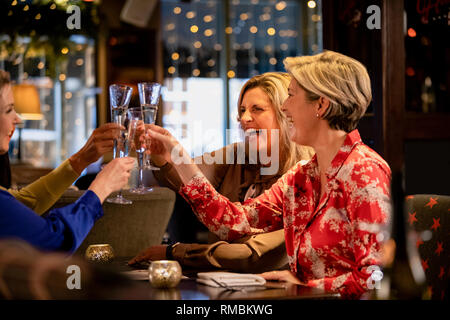 Small group of mature female friends making a celebratory toast while sitting around a table in a restaurant. Stock Photo