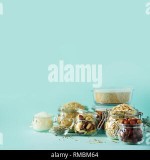 Grains, cereals, nut, dry fruits in glass jars over blue background with copy space. Clean eating, healthy, vegan diet concept. Stock Photo