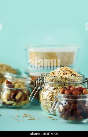 Grains, cereals, nut, dry fruits in glass jars over blue background with copy space. Clean eating, healthy, vegan diet concept. Stock Photo
