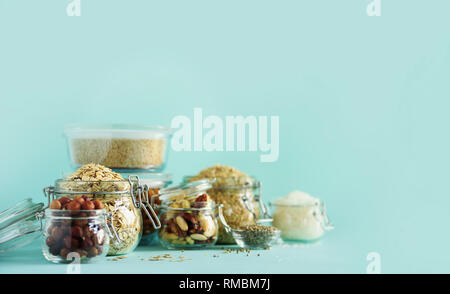 Grains, cereals, nut, dry fruits in glass jars over blue background with copy space. Clean eating, healthy, vegan diet concept. Stock Photo