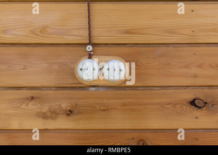 Electrical socket and switch in retro style on a wooden wall. Design of electricians in the house. Stock Photo