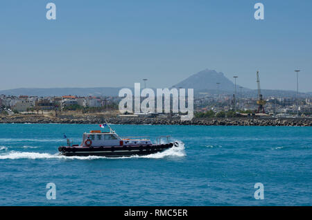 Pilot boat sailing on the azure sea in the Harbor of Heraklion on the background of the mountain top and the city (Greece) Stock Photo