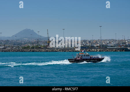 Pilot boat sailing on the azure sea in the Harbor of Heraklion on the background of the mountain top and the city (Greece) Stock Photo