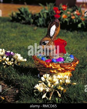 Easter basket with Easter bunny in the garden surrounded by crocuses. Stock Photo