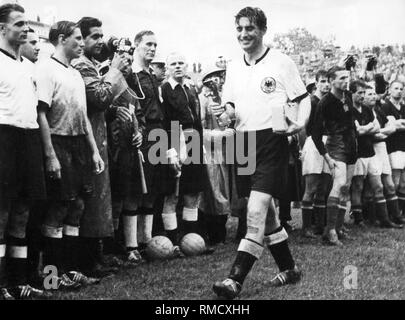 After winning the final of the 1954 FIFA World Cup, the captain of the victorious German national team, Fritz Walter walks smiling past fellow players and linesmen with the trophy. Stock Photo