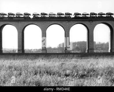 A train with new Golf II cars on a railway bridge. Stock Photo