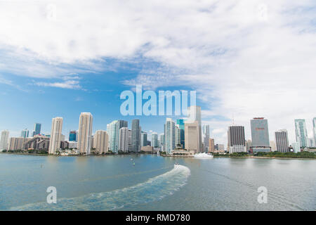 Aerial view of Miami skyscrapers with blue cloudy sky, white boat sailing next to Miami downtown. miami luxury property, modern buildings and yachts, successful life concept