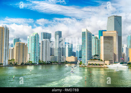 Aerial view of Miami skyscrapers with blue cloudy sky, white boat sailing next to Miami downtown. miami luxury property, modern buildings and yachts