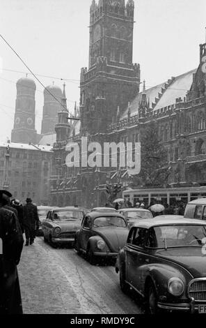 Road traffic at Marienplatz in Munich on Christmas Eve, 1961. On the right, the Christmas tree in front of the town hall, in the background the church towers of the Frauenkirche. On the road, cars of the brands VW Beetle and Borgward. Stock Photo