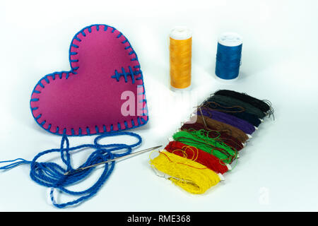 Hand stitched textile heart and colored sewing threads isolated on white background for romantic relationship, Valentines Day, broken heart and concep