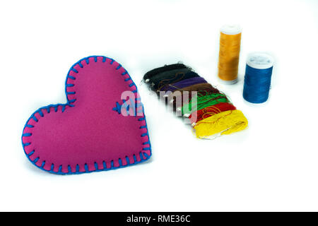 Hand stitched textile heart and colored sewing threads isolated on white background for romantic relationship, Valentines Day, broken heart and concep Stock Photo