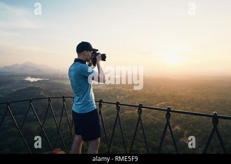 Young photographer with camera at the sunset. View from Sigiriya rock in Sri Lanka. Stock Photo