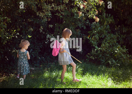 Two children hunting for butterflies in a back yard Stock Photo