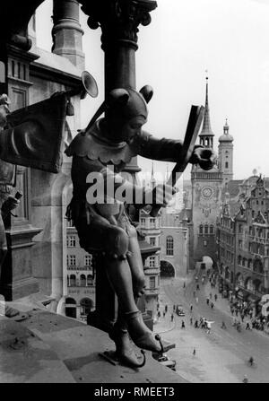 The Glockenspiel and a fool-figure at the Neue Rathaus (New Town Hall) in Munich. Right-hand side of the picture the Alte Rathaus (Old Town Hall) and the tower of the Heilig Geist Kirche. Stock Photo