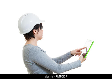 Side view of cheerful young woman engineer wearing protective helmet using a tablet computer gadget looking up isolated over white background with cop Stock Photo