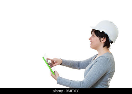 Side view of smiling young woman engineer wearing protective helmet using a pc tablet computer gadget looking up isolated over white background with c Stock Photo