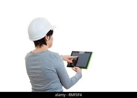 Rear view of young woman engineer wearing protective helmet using a tablet computer gadget to calculate looking up isolated over white background with Stock Photo