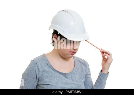 Thoughtful young woman engineer wearing protective helmet thinking pointing pencil to head isolated over white background with copy space. Stock Photo