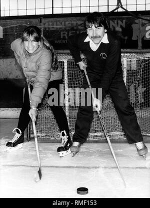 Ice hockey referee Nicole and Josef Kompalla with hockey sticks and puck in front of the goal on the ice. Stock Photo