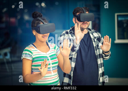 Multiracial young couple conecting with VR glasses indoor – Virtual reality concept with two young friends having fun with headset goggles during VR e Stock Photo
