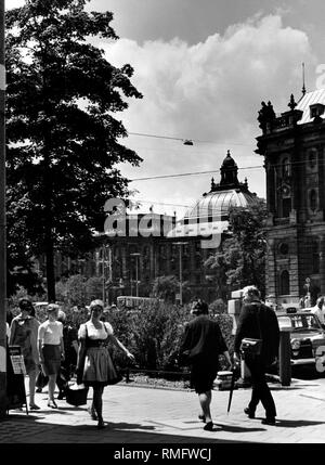 The Justizpalast (Palace of Justice) at Karsplatz in Munich. In front pedestrians and a woman wearing a traditional dress (undated picture). Stock Photo