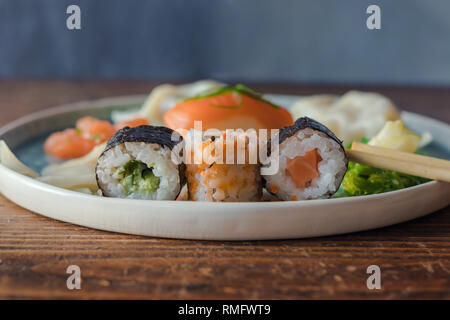 Sushi and sushi roll served on a plate on a wooden table. Front view, Japanese food