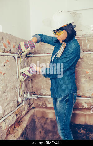 Clever woman repairing her bathroom sink pipe with  positive attitude. Using measuring tape ruler. Stock Photo