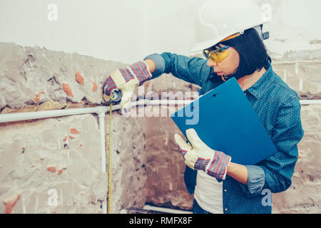 Woman working on new installations of bathroom pipes and using measuring tape - Image Stock Photo