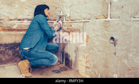 Clever woman repairing her bathroom sink pipe with  positive attitude. using a work tool. Selective focus and small depth of field Stock Photo