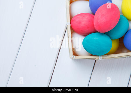 Easter, holidays, tradition and object concept - close up of colored easter eggs in basket Stock Photo