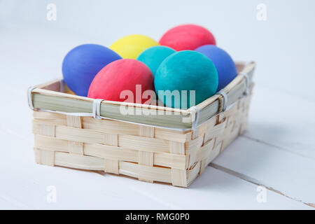 Easter, holidays, tradition and object concept - close up of colored easter eggs in basket Stock Photo