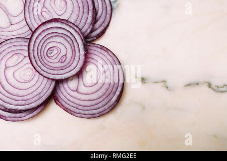 Closeup slices of fresh red onion placed on white marble tabletop Stock Photo