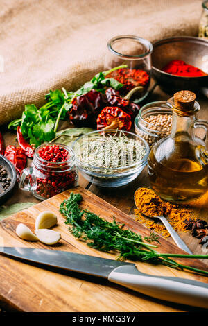 From above various spices and bottle of oil placed on timber tabletop near sharp knife Stock Photo