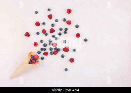 Creative Summer concept composition flat lay top view sweet fresh red raspberries blueberries ice cream waffle cone pink background copy space Templat Stock Photo