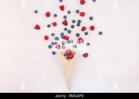 Creative Summer concept composition flat lay top view sweet fresh red raspberries blueberries ice cream waffle cone pink background copy space Templat Stock Photo