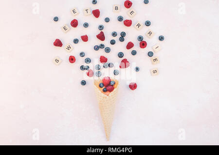 Creative Summer concept composition flat lay top view sweet fresh red raspberries blueberries ice cream waffle cone pink background copy space Templat Stock Photo
