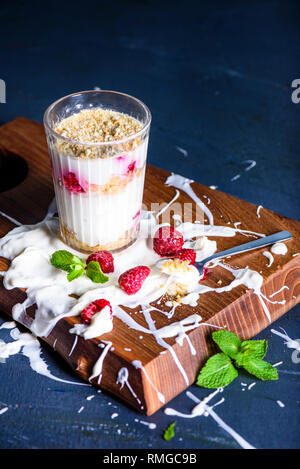 Raspberry cream cheese dessert. Greek yogurt raspberry biscuit parfait on a wood background. Stock Photo