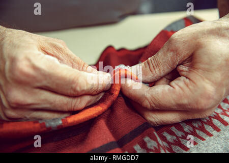 The senior man working in his tailor shop, tailoring, close up. Textile vintage industrial. The man in female profession. Gender equality concept Stock Photo