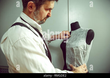 Closeup of tailors table with male hands tracing fabric making pattern for clothes in traditional atelier studio. The man in female profession. Gender equality concept Stock Photo