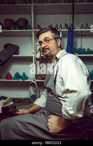 Enjoying process of creation custom made shoes. Workplace of shoe designer. Hands of shoemaker with cobbler tool Stock Photo