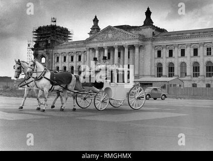 This photograph shows in the foreground a coach with two coachmen and in the background the Reichstag that is currently under reconstruction. The architect Paul Baumgarten restored the Reichstag until 1973. At that time, the utilization of the building was still unclear. The Reichstag was built in 1884 in the style of the Italian High Renaissance with elements of the German Renaissance and the Neo-Baroque. A special novelty was the dome construction made of glass and steel. Stock Photo