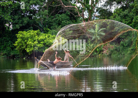 Fishermen on Nhu Y river, part of the Perfume River in Hue city, Vietnam. The man throwing the net has just slipped and is about falling into the wate Stock Photo
