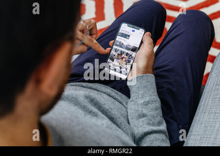 LONDON, UK - SEP 21, 2018: Man using the new Apple iPhone Xs with the immense OLED retina display and a12 bionic chip, looking over the app application looking pn photos app  Stock Photo
