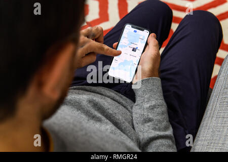 LONDON, UK - SEP 21, 2018: Man using the new Apple iPhone Xs with the immense OLED retina display and a12 bionic chip, looking over the app application looking pn photos app  Stock Photo